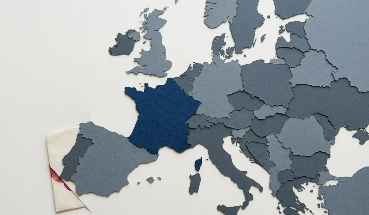 Carte de l’Europe avec la France en bleu profond, morceau d’enveloppe marquant le contexte administratif des documents pour un travailleur étranger en france